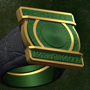 May include: A ring featuring a dark gray textured band with a green interior. The top of the ring displays a rectangular gold frame surrounding a green circular emblem with concentric rings, set against a textured green background surface.