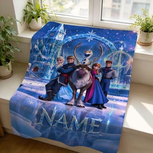 Puede incluir: Una manta de forro polar azul con una escena impresa de los personajes de Frozen, incluyendo a Elsa, Anna, Kristoff, Sven y Olaf, sobre un fondo de castillo helado con copos de nieve. La palabra NAME está impresa en letras azul hielo.