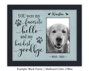 May include: A black framed photo memorial with a blue mat. The photo is of a golden retriever. The text reads "YOU were my favorite hello and my hardest goodbye ~2010-2021~ Winston".