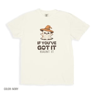 Ivory Comfort Colors t-shirt printed with the words If You'Ve Got It Haunt It and a drawing of a cute retro cartoon ghost wearing a witch hat, folded flat lay