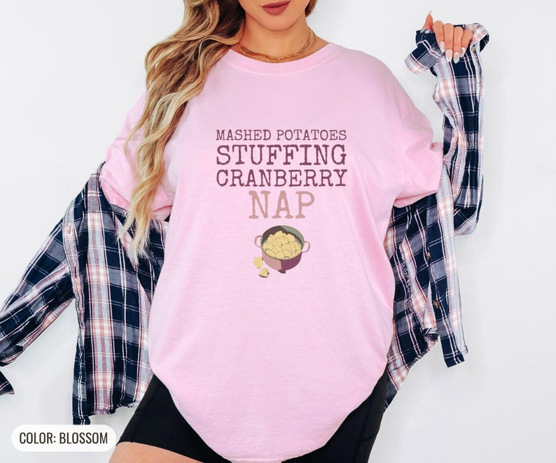 Blossom Comfort Colors t-shirt printed with the words Mashed Potatoes Stuffing Cranberry Nap and a drawing of a heavy enamel-coated cast iron Dutch oven filled with creamy mashed potatoes, steam lines, worn by a woman