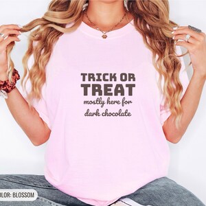 Blossom Comfort Colors t-shirt printed with the words Trick Or Treat Mostly Here For Dark Chocolate, worn by a woman