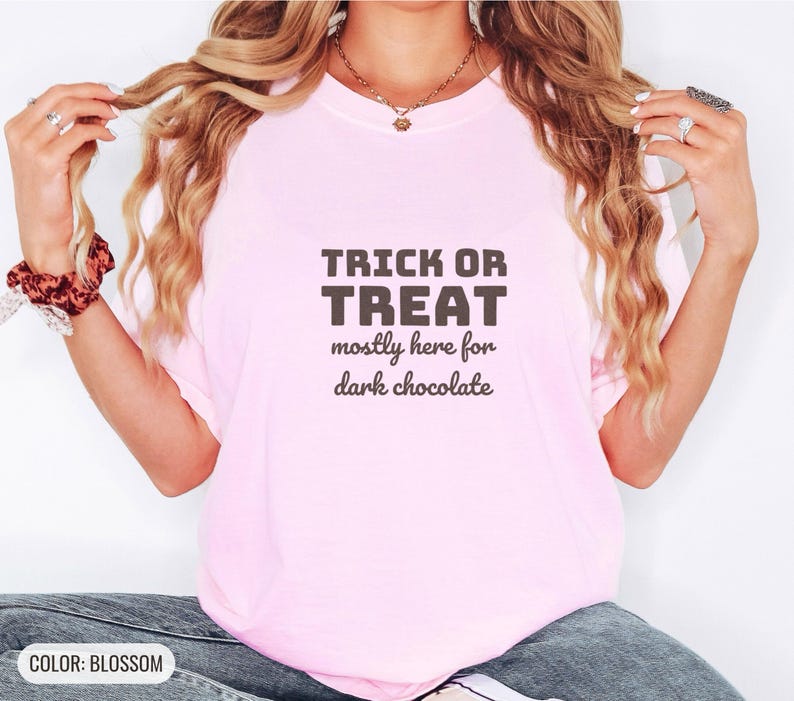 Blossom Comfort Colors t-shirt printed with the words Trick Or Treat Mostly Here For Dark Chocolate, worn by a woman