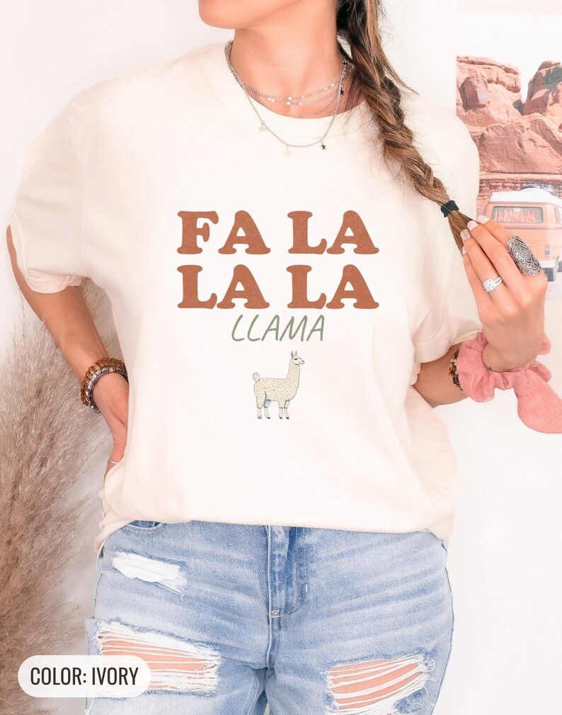 Ivory Comfort Colors t-shirt printed with the words Fa La La La Llama and a drawing of a fluffy llama, worn by a woman