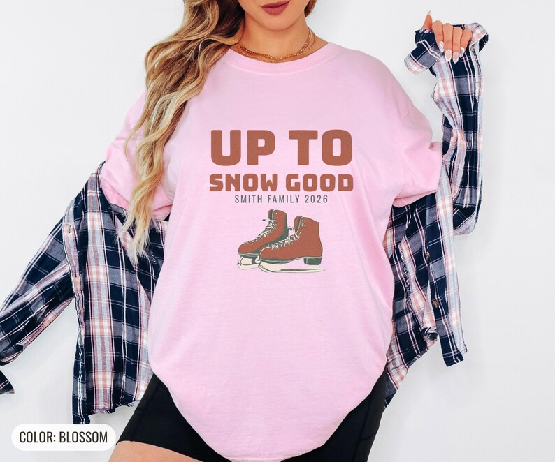 Blossom Comfort Colors t-shirt printed with the words Up To Snow Good Smith Family 2026 and a drawing of a vintage metal clamp-on ice skate with red laces, worn by a woman
