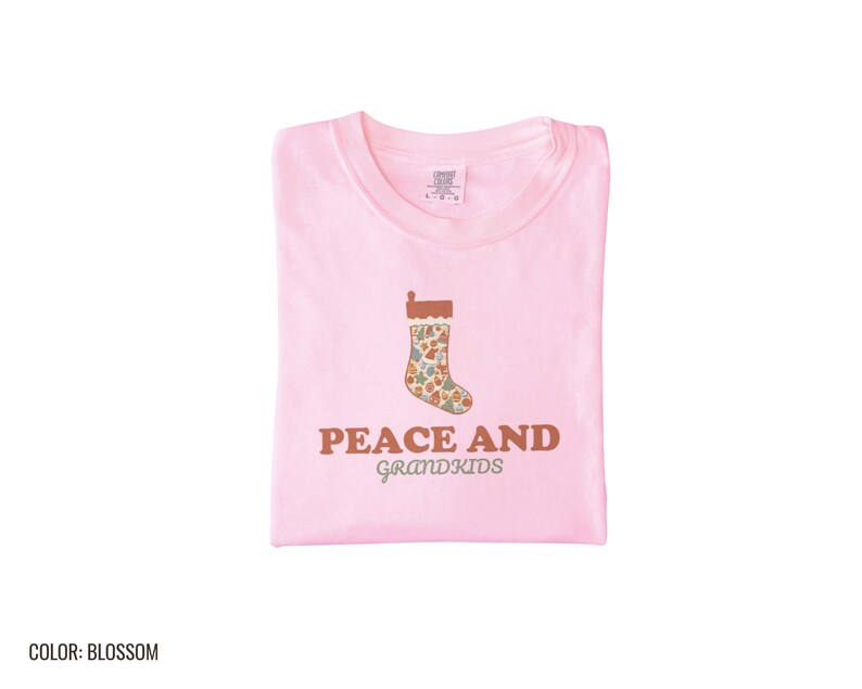 Blossom Comfort Colors t-shirt printed with the words Peace And Grandkids and a drawing of a classic knitted wool christmas stocking stuffed with small toys, folded flat lay