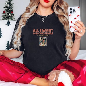 Black Comfort Colors t-shirt printed with the words All I Want For Christmas Is A Quiet Shift and a drawing of a pair of patterned compression socks hanging like Christmas stockings, worn by a woman