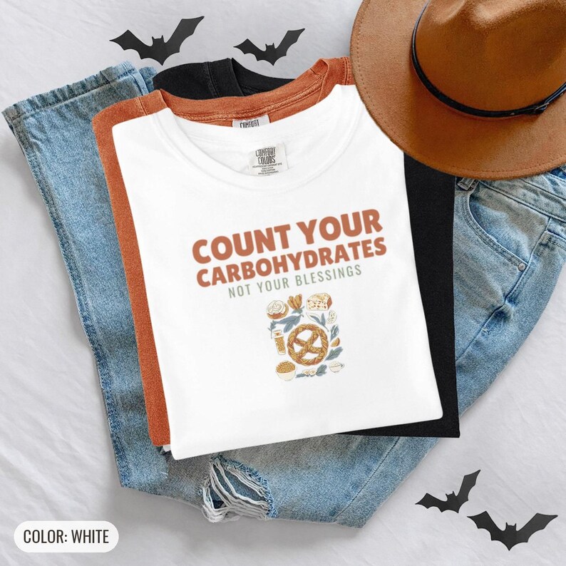 White Comfort Colors t-shirt printed with the words Count Your Carbohydrates Not Your Blessings and a drawing of a golden-brown braided pretzel with coarse salt grains, worn by a woman