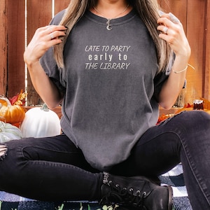 Pepper Comfort Colors t-shirt printed with the words Late To Party Early To The Library, worn by a woman