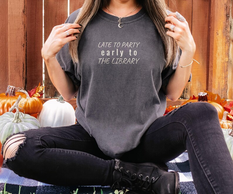 Pepper Comfort Colors t-shirt printed with the words Late To Party Early To The Library, worn by a woman