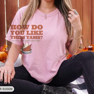 Blossom Comfort Colors t-shirt printed with the words How Do You Like Them Yams? With Extra Marshmallows and a drawing of a roasted yam sliced in half with melted marshmallow topping, worn by a woman