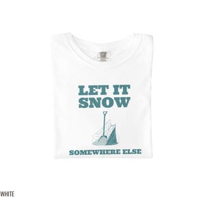 White Comfort Colors t-shirt printed with the words Let It Snow Somewhere Else and a drawing of a metal snow shovel propped beside an empty bag of rock salt, folded flat lay