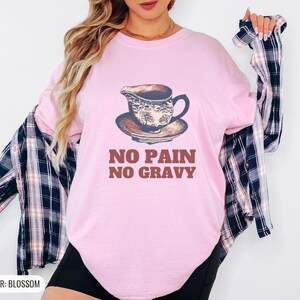 Blossom Comfort Colors t-shirt printed with the words No Pain No Gravy and a drawing of a ceramic gravy boat with a small puddle of gravy underneath, worn by a woman
