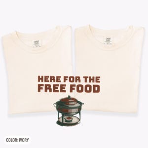 Ivory Comfort Colors t-shirt printed with the words Here For The Free Food and a drawing of a stainless steel chafing dish with steam rising off the lid, two matching shirts