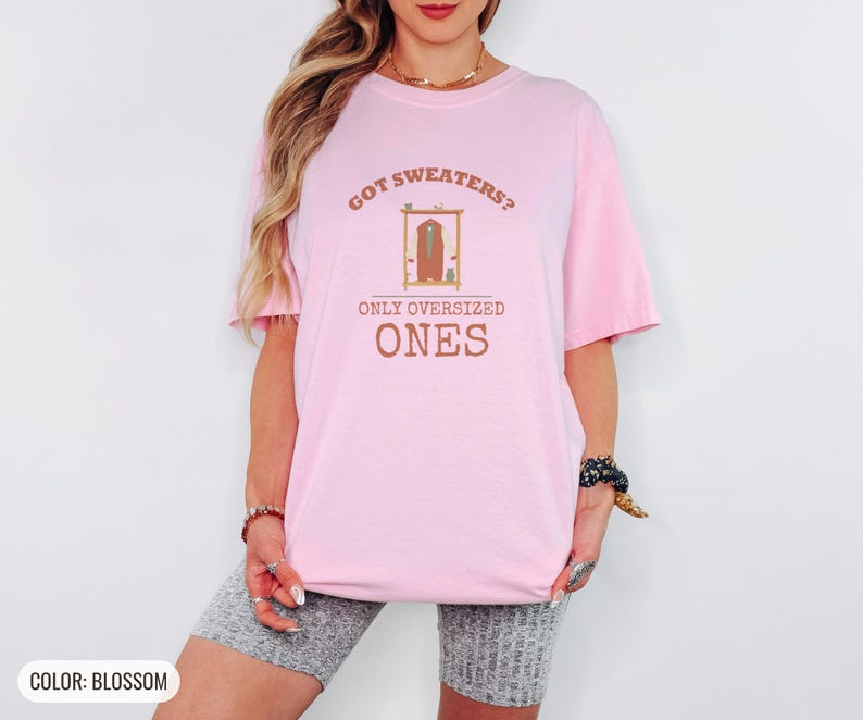 Blossom Comfort Colors t-shirt printed with the words Got Sweaters? Only Oversized Ones and a drawing of a knitted wool cardigan hanging from a simple wooden clothes hanger, worn by a woman