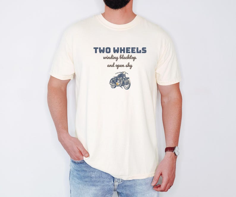 Ivory Comfort Colors t-shirt printed with the words Two Wheels Winding Blacktop And Open Sky and a drawing of a classic cruiser motorcycle in side profile, worn by a man