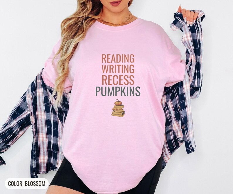 Blossom Comfort Colors t-shirt printed with the words Reading Writing Recess Pumpkins and a drawing of a stack of three vintage schoolbooks with a small orange pumpkin sitting on top, worn by a woman