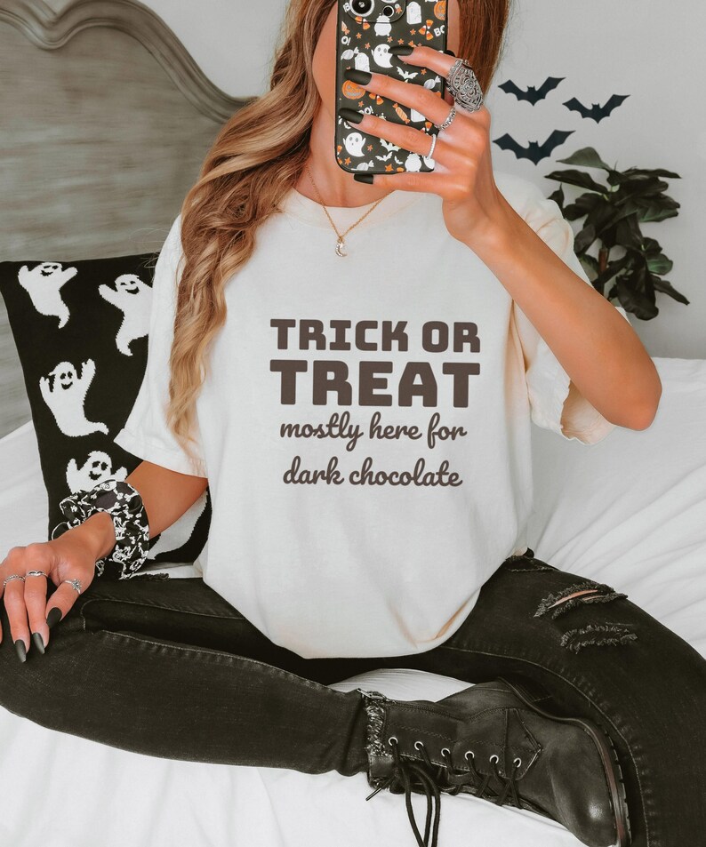 Ivory Comfort Colors t-shirt printed with the words Trick Or Treat Mostly Here For Dark Chocolate, worn by a woman