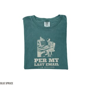Blue Spruce Comfort Colors t-shirt printed with the words Per My Last Email I Am Deceased and a drawing of a skeleton sitting at an office desk typing on a computer keyboard, folded flat lay