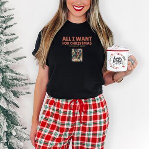 Black Comfort Colors t-shirt printed with the words All I Want For Christmas Is A Quiet Shift and a drawing of a pair of patterned compression socks hanging like Christmas stockings, worn by a woman