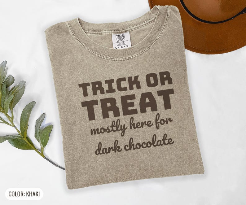 Khaki Comfort Colors t-shirt printed with the words Trick Or Treat Mostly Here For Dark Chocolate, folded flat lay