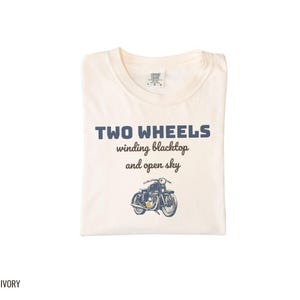 Ivory Comfort Colors t-shirt printed with the words Two Wheels Winding Blacktop And Open Sky and a drawing of a classic cruiser motorcycle in side profile, folded flat lay