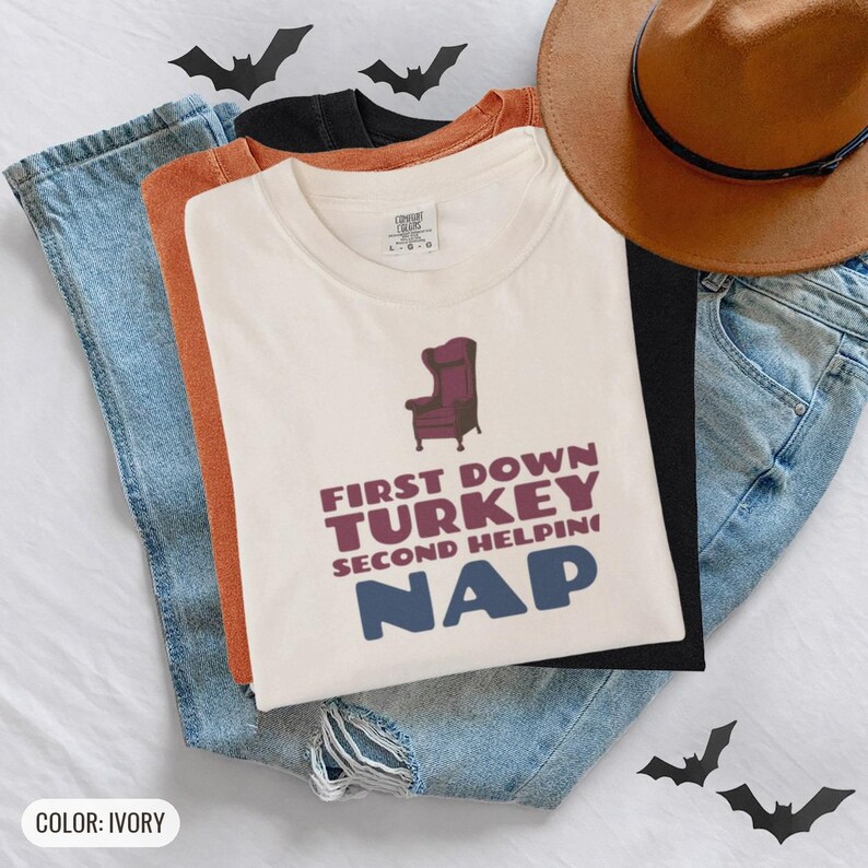 Ivory Comfort Colors t-shirt printed with the words First Down Turkey Second Helping Nap and a drawing of a vintage brown recliner with a footrest extended outward, worn by a woman