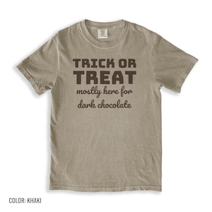 Khaki Comfort Colors t-shirt printed with the words Trick Or Treat Mostly Here For Dark Chocolate, folded flat lay