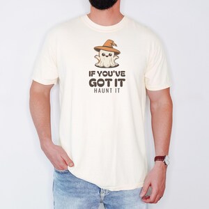 Ivory Comfort Colors t-shirt printed with the words If You'Ve Got It Haunt It and a drawing of a cute retro cartoon ghost wearing a witch hat, worn by a man