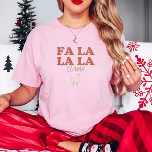 Blossom Comfort Colors t-shirt printed with the words Fa La La La Llama and a drawing of a fluffy llama, worn by a woman