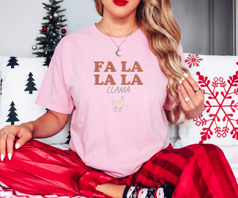Blossom Comfort Colors t-shirt printed with the words Fa La La La Llama and a drawing of a fluffy llama, worn by a woman