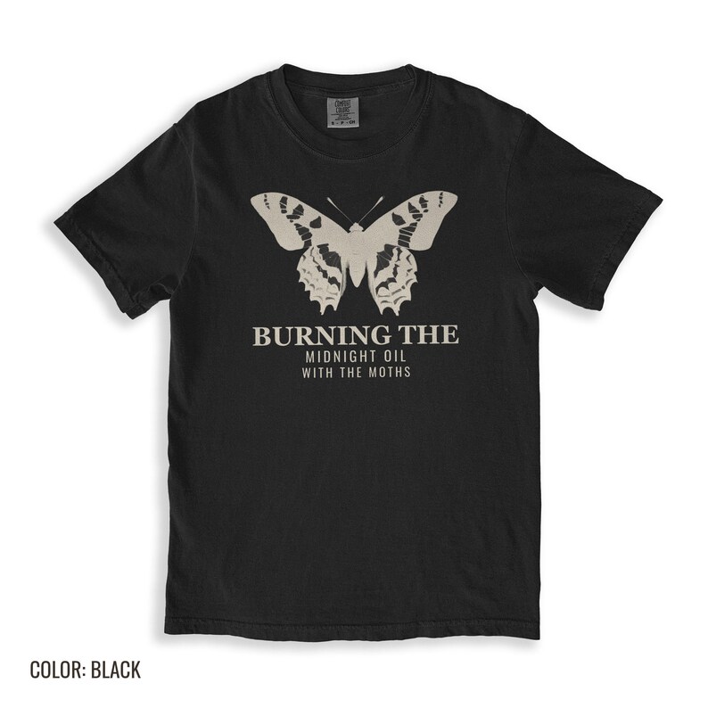 Black Comfort Colors t-shirt printed with the words Burning The Midnight Oil With The Moths and a drawing of a cecropia moth with feathery antennae, folded flat lay