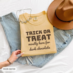Butter Comfort Colors t-shirt printed with the words Trick Or Treat Mostly Here For Dark Chocolate, folded flat lay