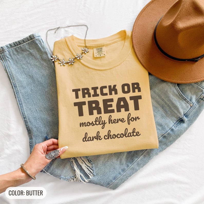 Butter Comfort Colors t-shirt printed with the words Trick Or Treat Mostly Here For Dark Chocolate, folded flat lay