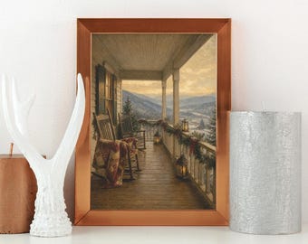 Puede incluir: Una impresión enmarcada que representa un porche de madera con dos mecedoras, una colcha y linternas con vistas a un paisaje montañoso nevado al atardecer. El marco es de cobre metálico, flanqueado por una escultura de asta blanca y una vela de pilar plateada texturizada.