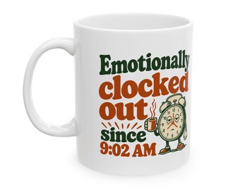 Puede incluir: Una taza de cerámica blanca con el texto en verde oscuro y naranja "Emotionally clocked out since 9:02 AM" junto a un gráfico de un despertador antropomórfico cansado que sostiene una taza de café humeante.