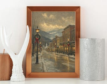 Puede incluir: Un cuadro enmarcado de una calle nevada al atardecer, con una farola negra con una corona, edificios de ladrillo y montañas al fondo. La obra de arte está encerrada en un marco de color cobre metálico.