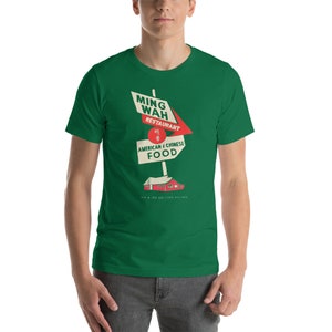May include: A green t-shirt with a vintage-style illustration of a restaurant sign that reads "Ming Wah Restaurant, American & Chinese Food".
