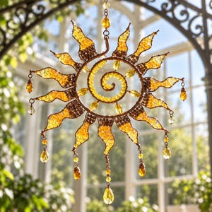 May include: A sun-shaped hanging ornament crafted from copper-toned wire and yellow glass beads. The design features a central spiral, radiating flame-like points, and dangling teardrop-shaped crystals suspended from the outer edges.