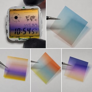 May include: A digital watch display module featuring a world map graphic and time readout of 10:54, alongside four square, semi-transparent gradient filter films in various colour combinations including blue, orange, yellow, and purple hues.