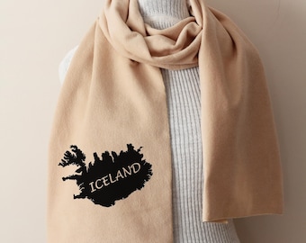 May include: A beige scarf with a black outline of Iceland and the word "ICELAND" printed on it.