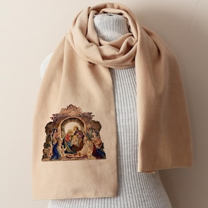 Puede incluir: Bufanda beige con una imagen religiosa detallada de la Natividad. La bufanda est&aacute; drapeada sobre un maniqu&iacute;, mostrando su longitud y textura. La imagen presenta figuras en varios colores.