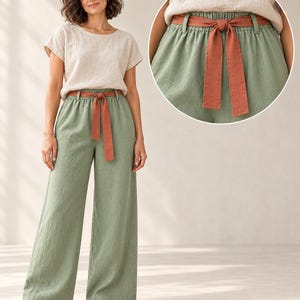 May include: Sage green wide-leg trousers featuring an elasticized waistband with a matching rust-colored fabric tie belt. The trousers are paired with a short-sleeved beige top and open-toe sandals, showcasing a clean, textured fabric finish.