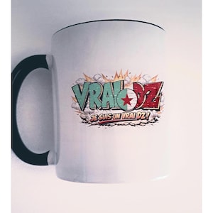 Peut inclure: Un mug en céramique blanc avec une anse noire, orné d'un motif graphique portant le texte VRAI DZ et JE SUIS UN VRAI DZ ! Le design comprend un emblème circulaire avec une étoile rouge et un arrière-plan style explosion en vert et rouge.