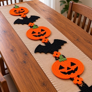 Puede incluir: Un camino de mesa decorativo de ganchillo largo con un patrón repetitivo de calabazas de color naranja brillante con tallos verdes, murciélagos negros con alas extendidas y pequeñas flores naranjas, todo conectado en una línea sobre un camino de tela beige.