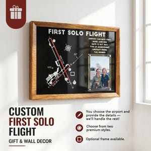 May include: A rectangular wooden frame containing a black display board with a white airport runway diagram, a compass rose, and text reading FIRST SOLO FLIGHT, AIRPORT: VAN NUYS (VNY), NAME: JANE DOE, DATE: 12 OCT 2023, and a photo of two people.