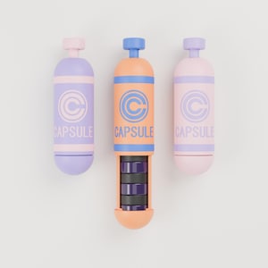 May include: Three cylindrical capsule containers arranged vertically. The left is lavender, the center is orange with an open section revealing dark stacked discs, and the right is light pink. Each features a circular C logo and the text CAPSULE.