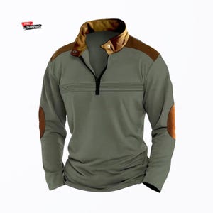 Op de afbeelding: Een shirt met lange mouwen in olijfgroen met een bruine kraag en schouderstukken, een kwartritssluiting aan de voorzijde en bruine elleboogstukken. Het borstgedeelte is voorzien van horizontale lijndetails over de voorkant van het kledingstuk.