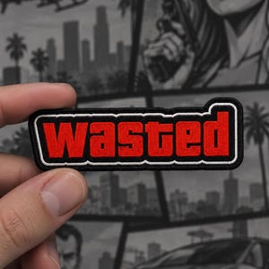 May include: A rectangular embroidered patch featuring the word WASTED in bold red capital letters. The text is outlined in a thick white border, which is then surrounded by a black border, creating a distinct layered effect for the design.