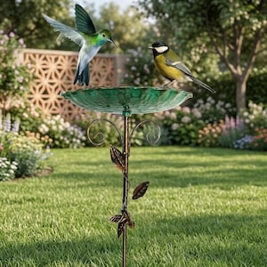 Può includere: Un bagno per uccelli con una vaschetta in vetro verde traslucido dalla superficie testurizzata, sostenuta da un supporto in metallo scuro decorato con foglie e volute metalliche, con un colibrì e una cinciallegra vicino alla vaschetta.